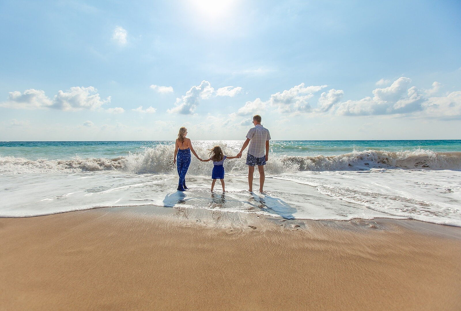 man woman and child walking on beach